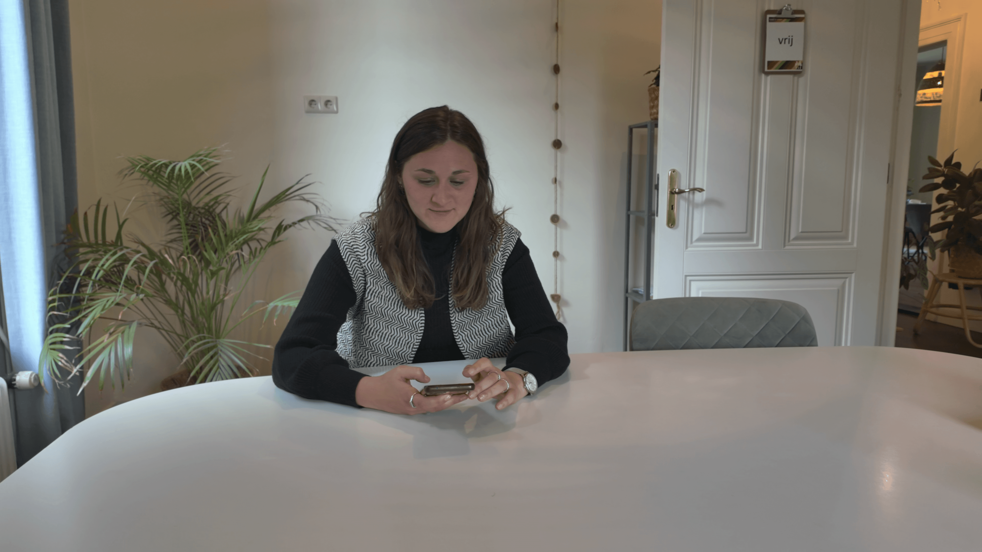 Een medewerker van Kind & meer bekijkt haar telefoon aan tafel
