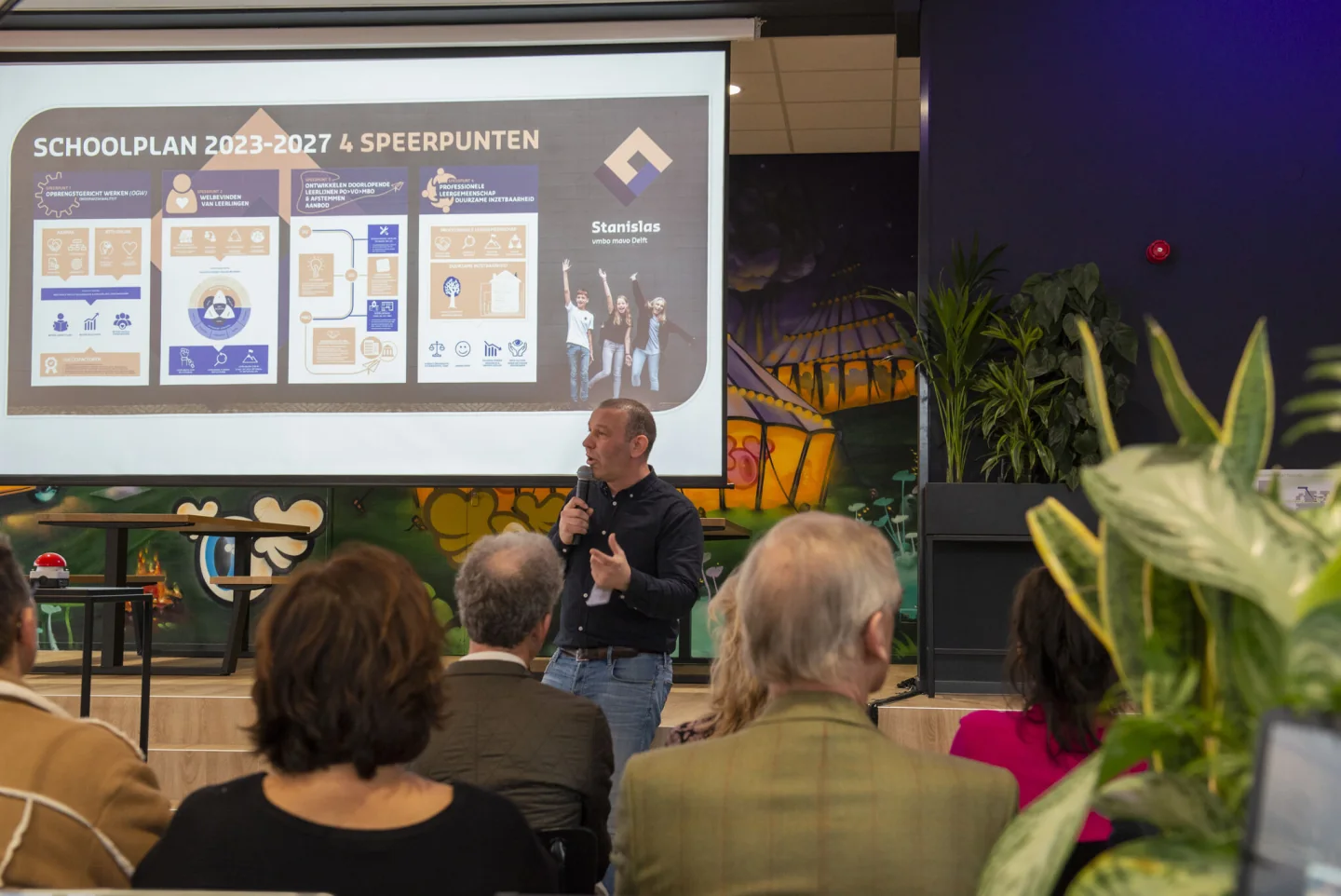 Rowdy Lagraauw spreekt met een microfoon voor collega’s bij Stanislas vmbo mavo Delft